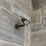 Security camera mounted on stone wall.