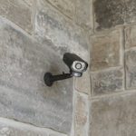 Security camera mounted on stone wall.
