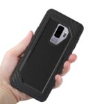 Hand holding a black rugged phone case with a smartphone inside.