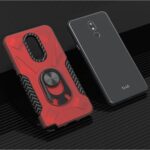 Two smartphone cases displayed on a black surface, one red and black with a ring holder, the other plain black.
