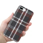 Hand holding a plaid-patterned phone case with black, white, and red lines.