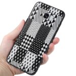 Hand holding a phone with a black and white geometric patterned case.