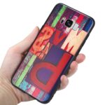 Hand holding a colorful phone case with bold text design.