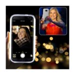 Two women taking selfies on smartphones with blurred lights background.