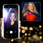 Two women taking selfies with smartphones, one showing on the phone screen.
