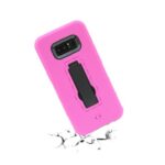 Pink phone case with built-in black kickstand on cracked surface.