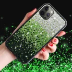 A hand holding a sparkling green and silver rhinestone phone case.