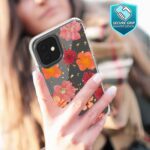Hand holding a smartphone with a floral case outdoors.