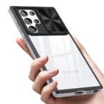 Hand holding a phone with a black lens protector on the camera area.
