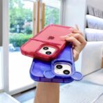 Hand holding two colorful iPhone cases, one red and one blue.