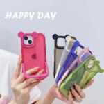 Colorful bear-shaped phone cases held in a hand with 'HAPPY DAY' text.