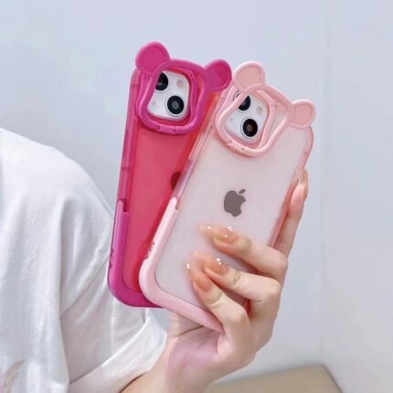 Two cute bear-themed phone cases, one pink and one clear, held in a hand.